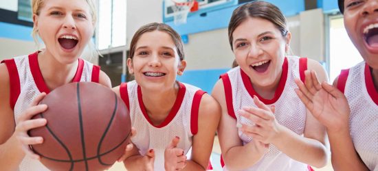 Portrait Of Female High School Basketball Team Celebrating On Court