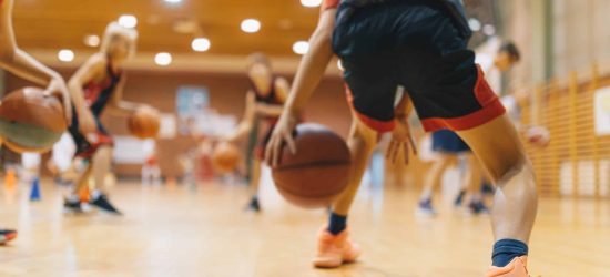 Young Basketball Player on Practice Session. Youth Basketball Team Bouncing Balls on Sports Court. Group of Kids Training Basketball Together